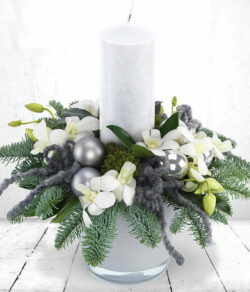 Silver Sheen Candle Arrangement. Candle arrangement featuring white Dendrobium orchids, green moss, blue spruce, grey baubles, and a central cream candle.