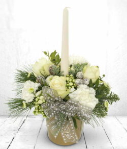 Icicle Candle Flower Arrangement White candle surrounded by white and cream roses, carnations, chrysanthemums, green foliage, pine cones and a festive bow in a gold pot.