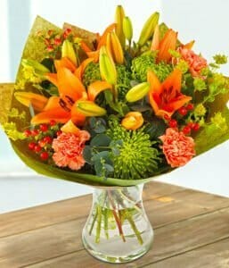 Gold Rush Flower Bouquet Featuring Orange Lilies, Green Chrysanthemums, Orange Carnations, Bupleurum, Red Hypericum Berries, And Eucalyptus Foliage In A Vibrant Design.