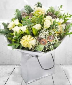 Snowy Forest Flower Bouquet Hand-tied bouquet featuring white spray roses, hyacinths, gypsophila, pine cones and pine foliage for a snowy forest-inspired look.