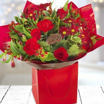 Festive Spirit Flower Bouquet Featuring Rich Red And White Blooms With Berries And Greenery, Elegantly Wrapped For The Holiday Season.