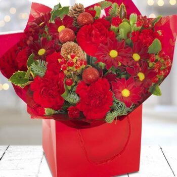 Christmas Cracker Flower Bouquet Featuring Rich Red And White Flowers, Festive Berries, And Greenery, Elegantly Wrapped For The Holiday Season.