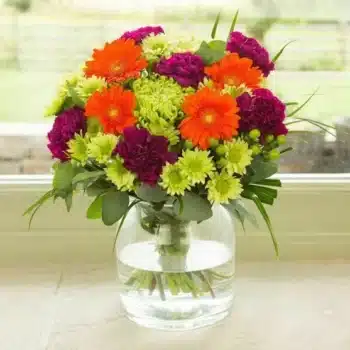 Tropical Fanfair Flower Bouquet Featuring Lime Blooms, Orange Gerberas And Purple Flowers, Hand-Tied For A Colourful, Tropical-Inspired Arrangement.