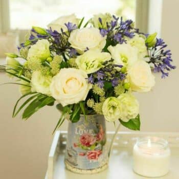 Congratulations Flower Bouquet Featuring Cream Roses, Blue Agapanthus, And Palm Leaves Arranged In A Classic, Elegant Design.