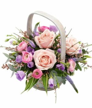 Pink And Mauve Flower Basket White-Wash Basket Filled With Pink Roses, Lavender Lisianthus, Veronica, Pink Ranunculus, Genista, And Lush Greenery In A Soft Pastel Design.
