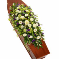 Coffin Spray Featuring White Lilies, Roses, And Greenery Arranged In A Long, Elegant Design For A Funeral Tribute.