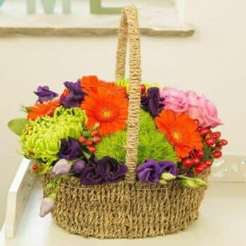 Citrus Flower Basket Featuring Orange Gerberas, Pink Roses, And Lime-Green Accents Arranged In A Bright, Contemporary Basket Design.