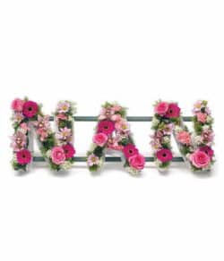 Nan Lettering Tribute Floral tribute spelling “Nan” with orchids, roses, and gerberas, arranged on a stand with ribbon edging for a dignified display.
