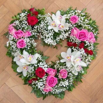 Orchid Heart-Shaped Wreath Featuring Cymbidium Orchids, Red And Pink Roses, Gypsophila, And Natural Seasonal Foliage
