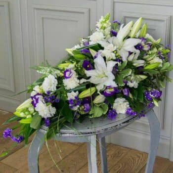 Memories Spray Arrangement Featuring White Oriental Lilies, White Carnations, Purple Lisianthus, And Fresh Green Foliage In A Single-Ended Teardrop Design.