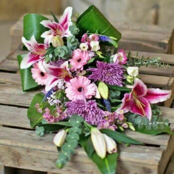 Seasonal Pink Spray Arrangement Featuring Pink Oriental Lilies, Pink Germini, Pink Anastasia Blooms, Pink Wax Flowers, And Lush Eucalyptus Foliage.