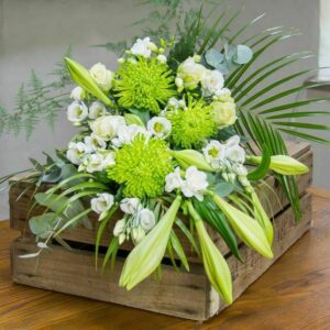 Natural Floral Spray Featuring White Roses, Longiflorum Lilies, And Lisianthus With Soft Green Foliage In A Graceful Elongated Design.