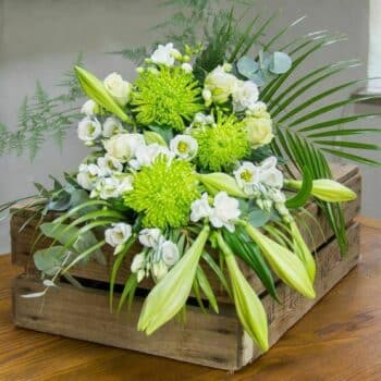 Natural Floral Spray Featuring White Roses, Longiflorum Lilies, And Lisianthus With Soft Green Foliage In A Graceful Elongated Design.