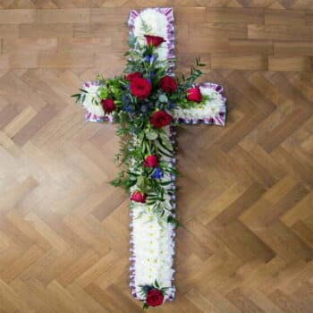 Floral Cross Arrangement Featuring A White Chrysanthemum Base, Detailed With Red And Blue Flowers, Finished With Pleated Ribbon Edging.