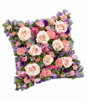 Pink And Mauve Cushion Tribute Featuring Roses, Ranunculus, Bouvardia, Carnations, Lisianthus, And Mixed Greenery In A Classic Design.