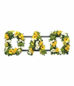 Dad Lettering Tribute featuring white Chrysanthemums and Carnations with yellow Roses, Germini, and Mimosa on a display stand.
