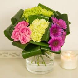 Quattro Flower Bouquet featuring lime, pink and purple blooms arranged in a grouped style with folded aspidistra leaves for a contemporary floral design.