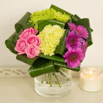 Quattro Flower Bouquet Featuring Lime, Pink And Purple Blooms Arranged In A Grouped Style With Folded Aspidistra Leaves For A Contemporary Floral Design.