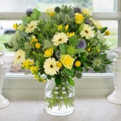 Sea Breeze Flower Bouquet featuring freesia, roses, subtle blue tones, and seasonal foliage arranged in a bright, elegant display.