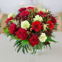 Guaranteed Smile Flower Bouquet with large red roses, lush foliage, red hypericum berries, and lime accents for a vibrant, elegant design.