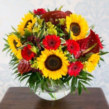 Mother Nature Flower Bouquet Featuring Bright Sunflowers, Tropical Green Anthuriums, And Rich Red Germini In A Bold, Colourful Arrangement.