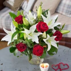 Lovable Flower Bouquet Hand-tied bouquet featuring vibrant red roses, elegant oriental white lilies, and textured green foliage, arranged beautifully for a romantic gift.