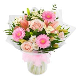 Sweetness And Light Flower Bouquet A hand-tied bouquet featuring soft pink and white roses, lilies, germini, and lisianthus, finished with lush seasonal foliage.